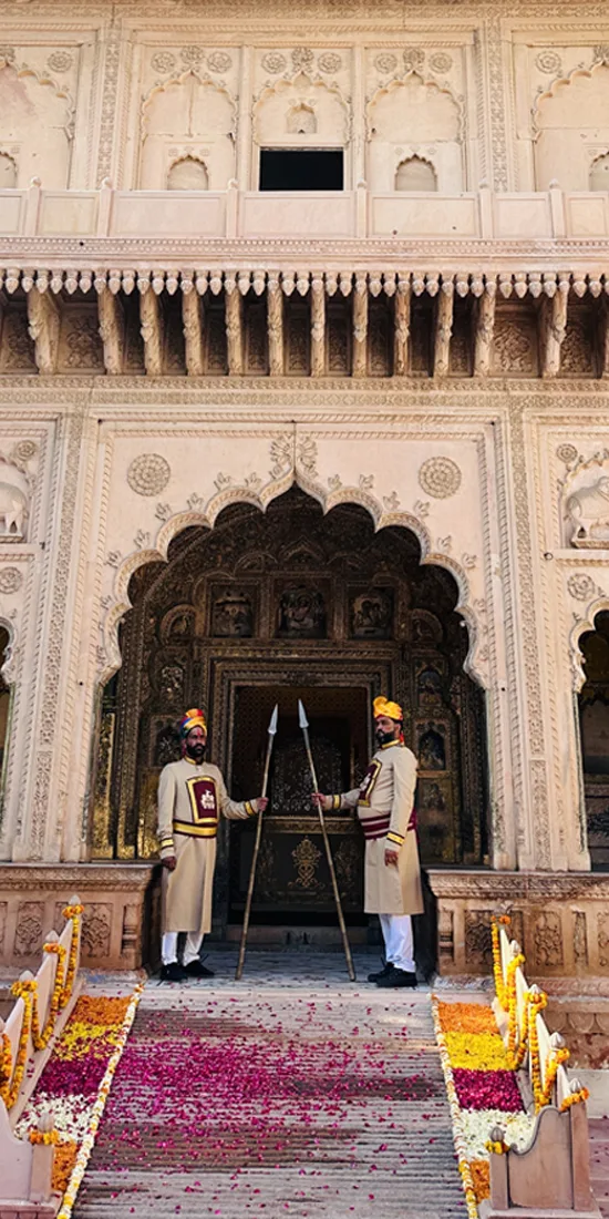 Traditional guards at the ornate, petal-strewn entrance of Mahal Khas Palace, Bharatpur